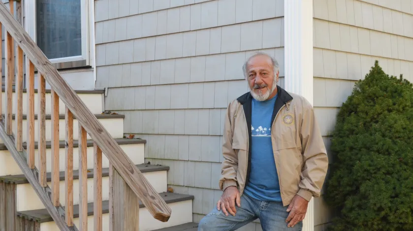 Richard Lalond stands on his back steps, smiling at the camera.
